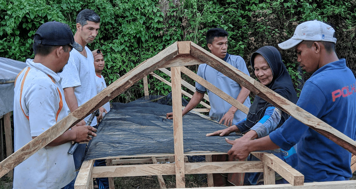 Indonesian villagers working on a roof with TCD members.