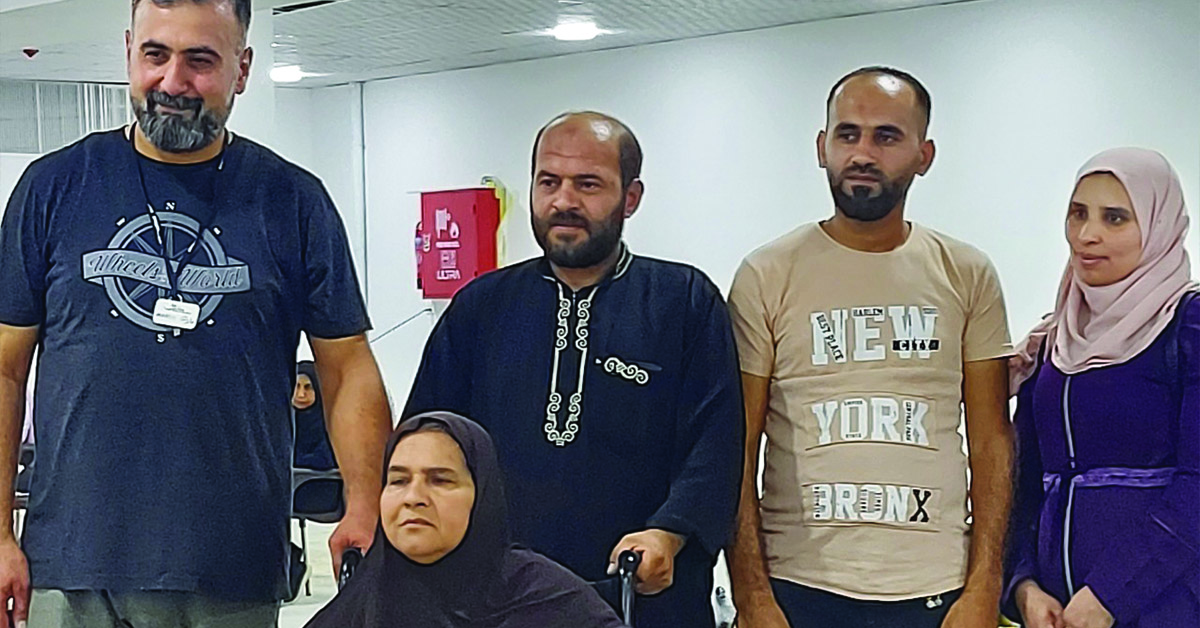 Jordan volunteers in a group photo with a recipient getting a donated wheelchair.