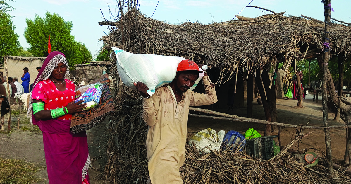 Pakistan man and woman caring emergency supplies provided by GHNI.