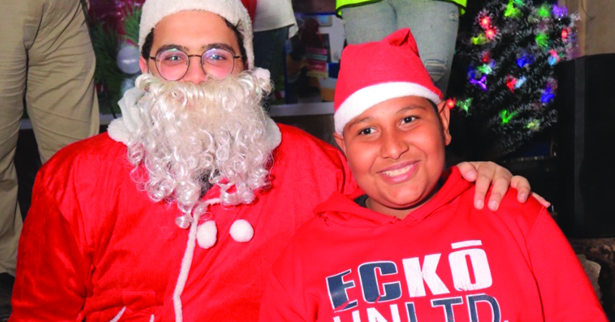 A TCD leader dressed as Santa and is with a child who was given a gift.