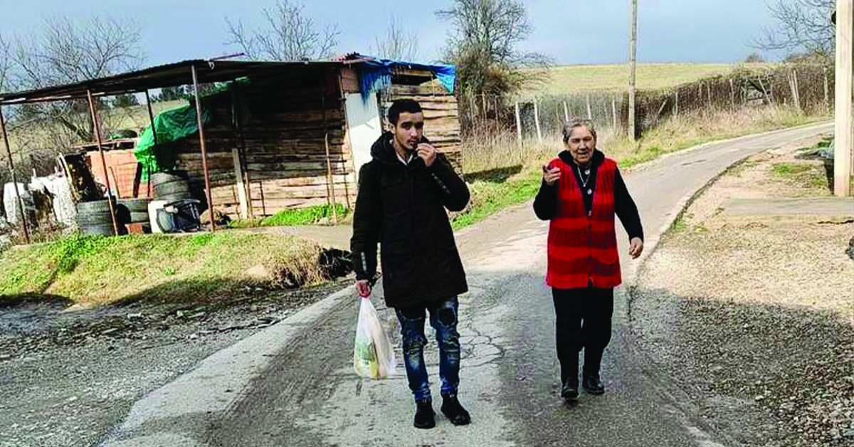 A young man and old lady walking on a beaten road.