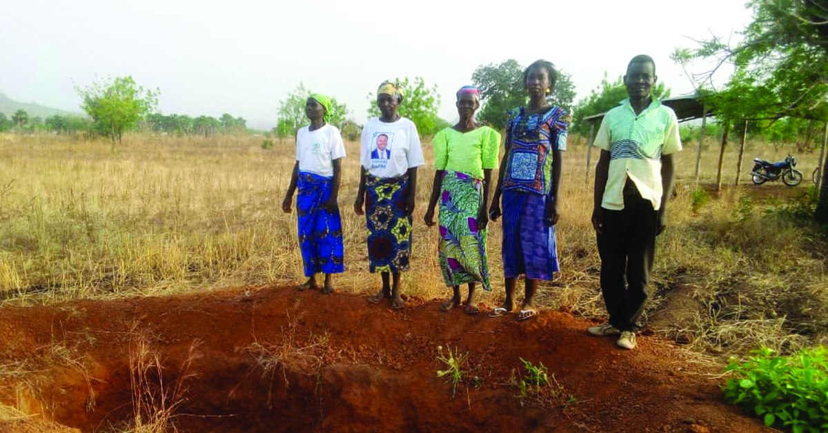 Villagers standing next to the latrine hole dug up.