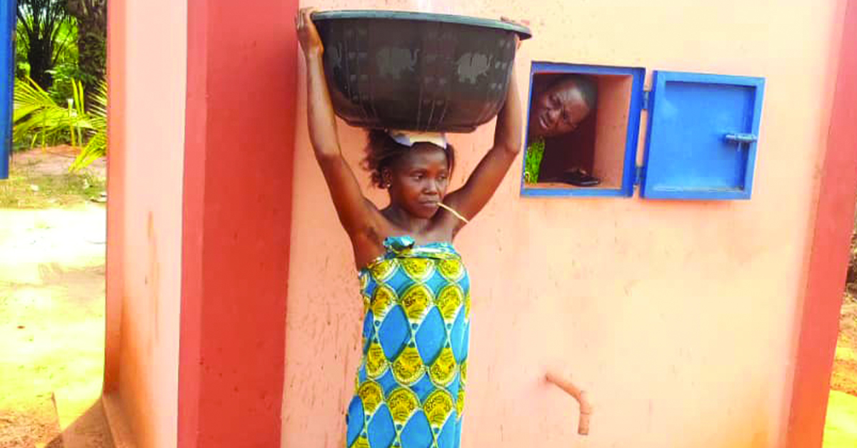 A village woman getting water with her wide bucket.