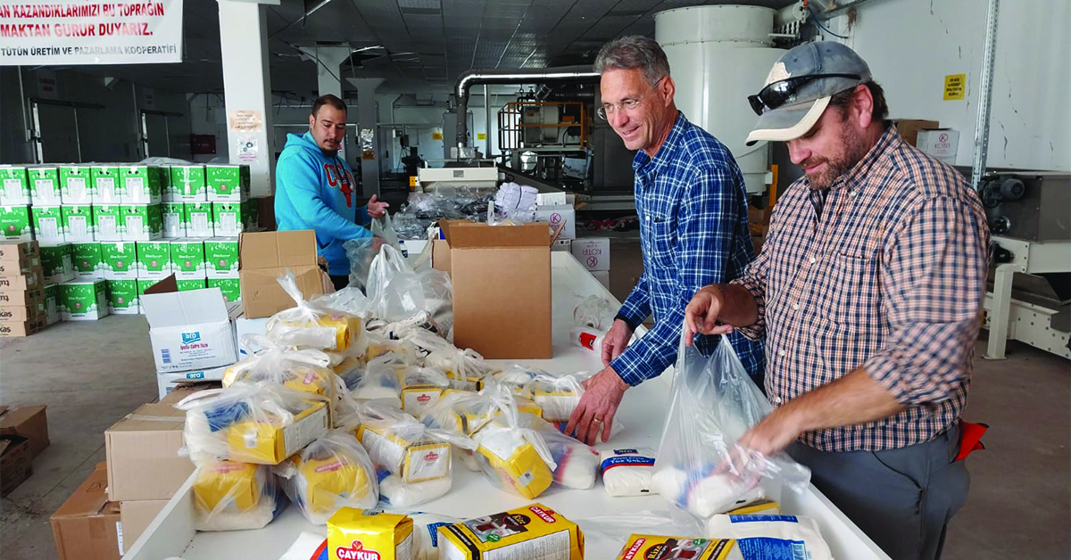 Three men sorting food for Turkey earthquake survivors.