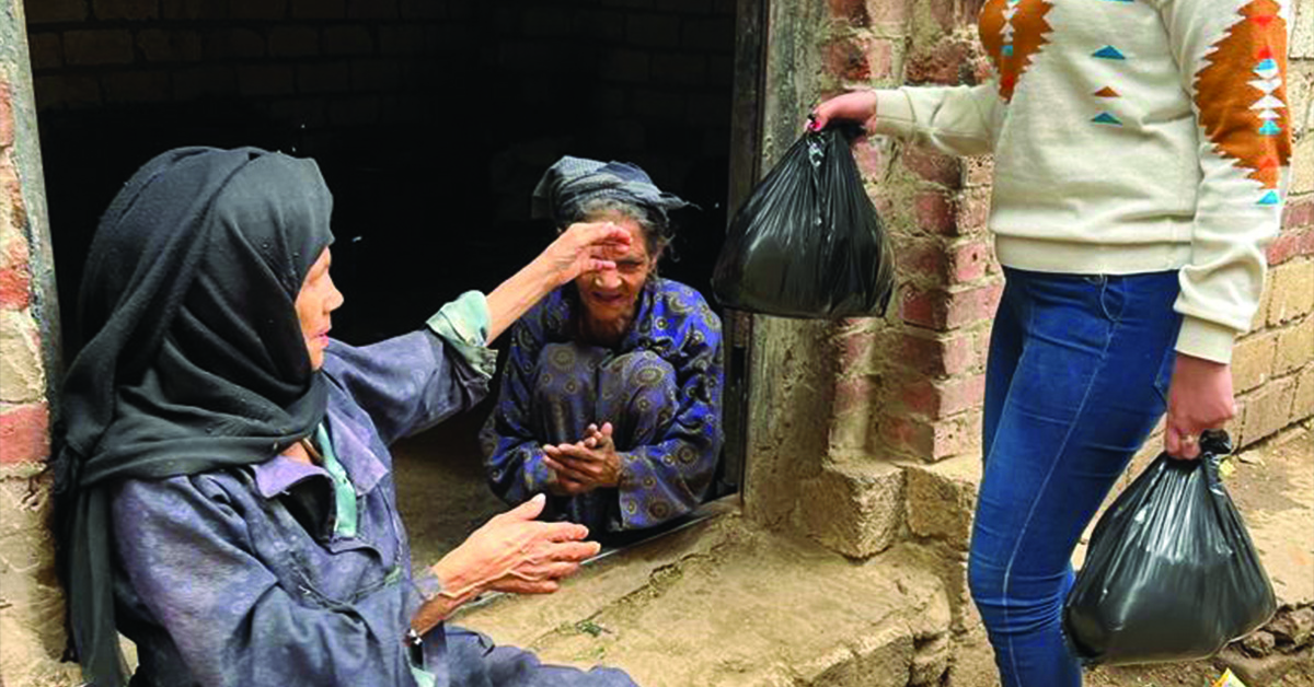 A TCD worker handing food to an Egyptian woman.