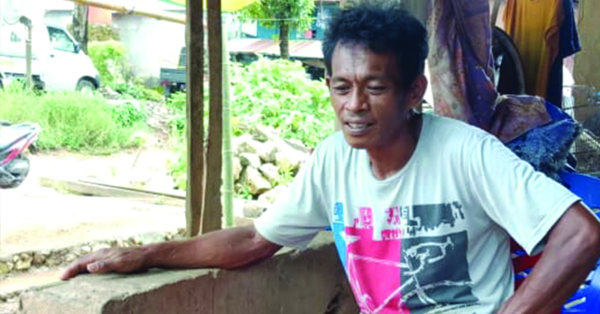 An Indonesian man sitting outdoors.