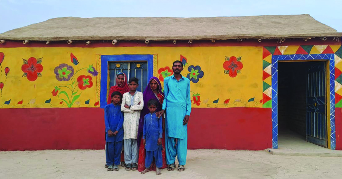 A Pakistanian family standing in front of their new house.