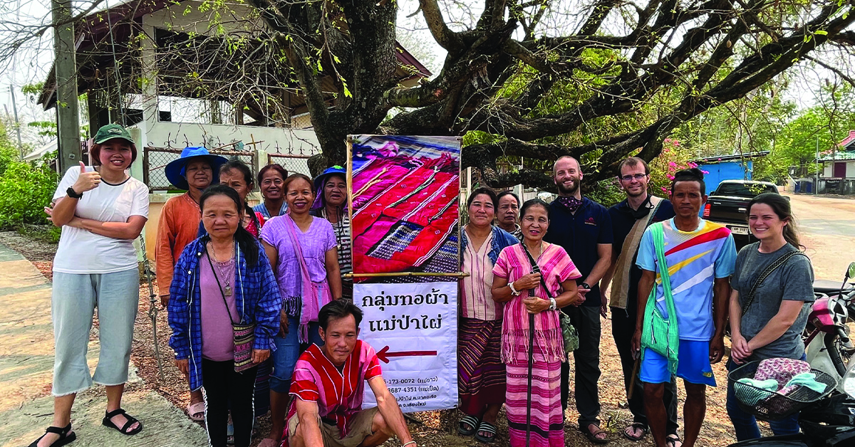 The Weaving Group standing with their marketing sign.