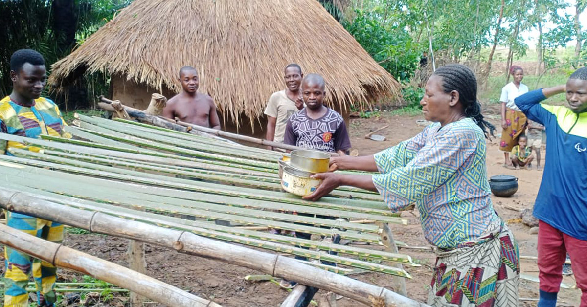 A Nigerian villager placing dishes on a newly constructed dish rack.