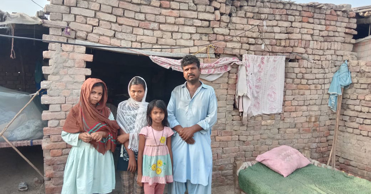 A Pakistan family in front of their damaged house.