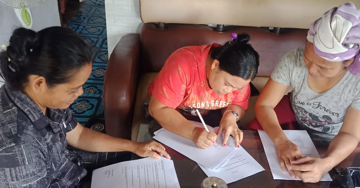 Mawa women signing documents.