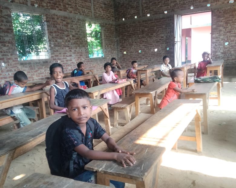 A classroom made of bricks, which houses classmates on their rectangular desks.