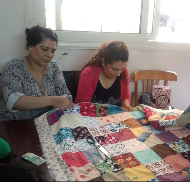 Two ladies making a quilt blanket through sewing.