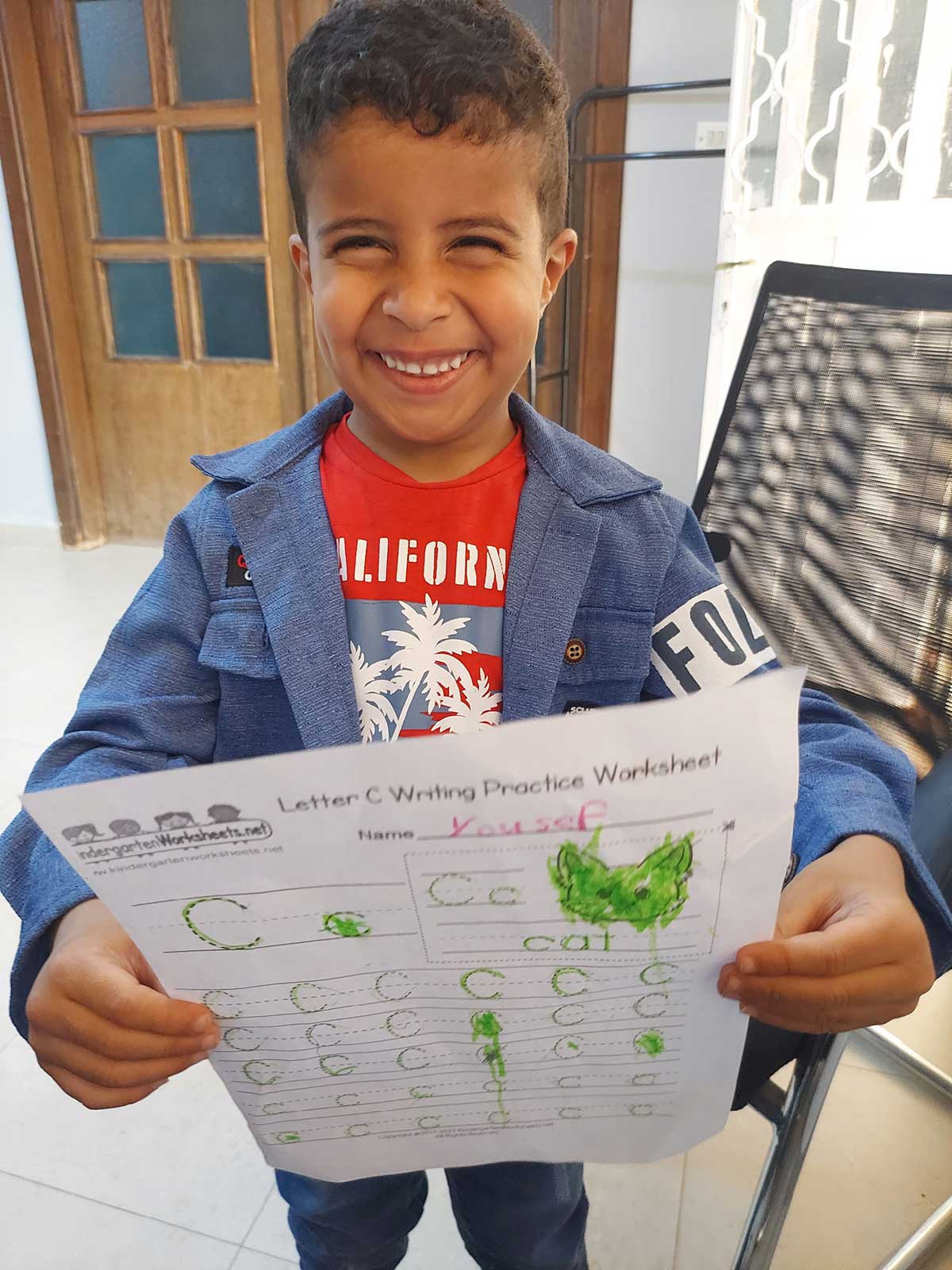 A boy student holding the English letter he created with his newfound skills.