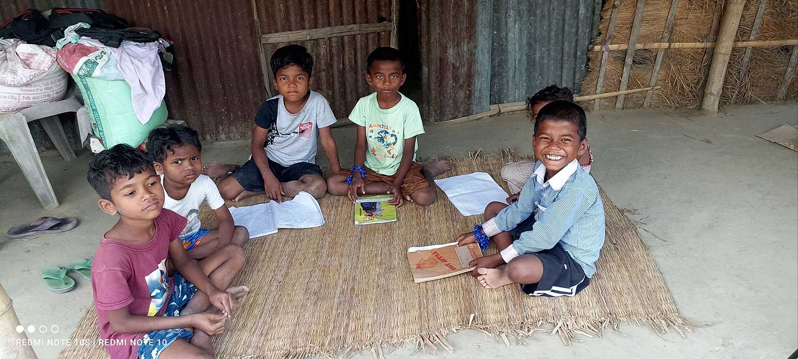 Four children on a straw carpet and doing a study session.