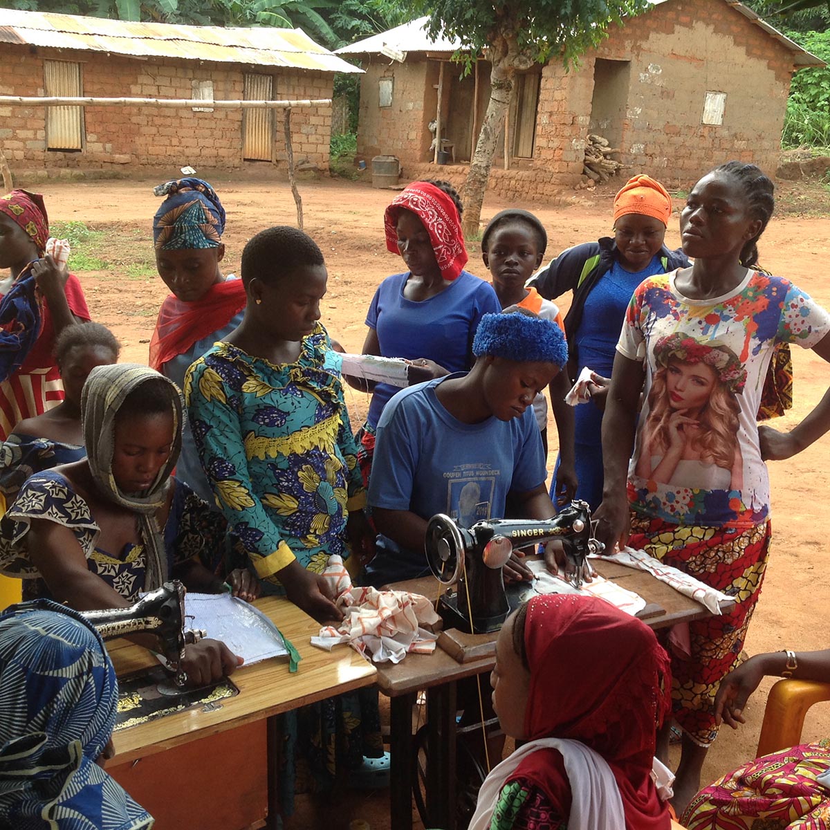 A group of Bankim villagers watching menstrual pads be sewn up.