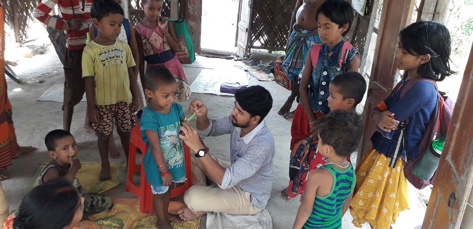 A small group of Binodpur children watching one of their own get a medical shot.