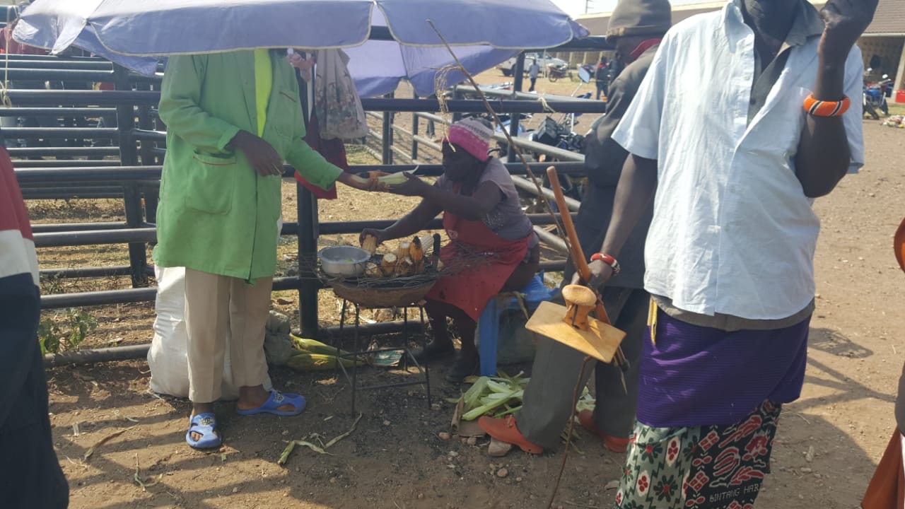 Maisha Bora villager, Mama Hanna, selling her maize w/ her small market table.