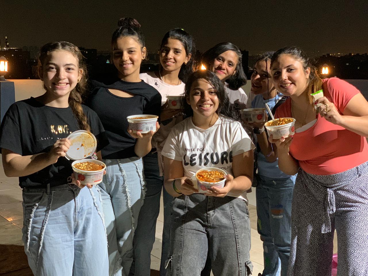 A group of teenagers posing for a photo with food in their hand.