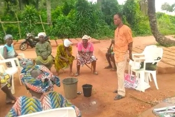 A TCD teacher demonstrating handwashing with his two buckets.