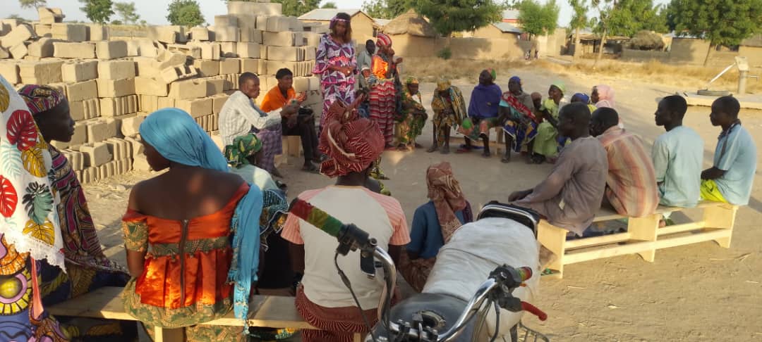 Four benches of four Ngassa villagers in a circle while they learn about income generation.