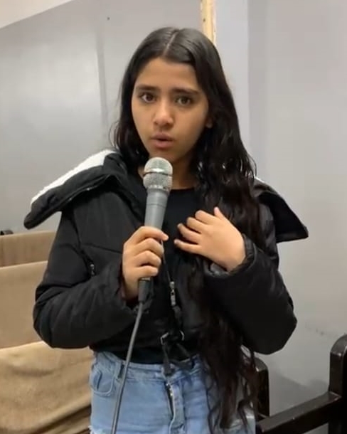 TCD attendant, Jumana Sami, speaking in front of the class with a microphone.