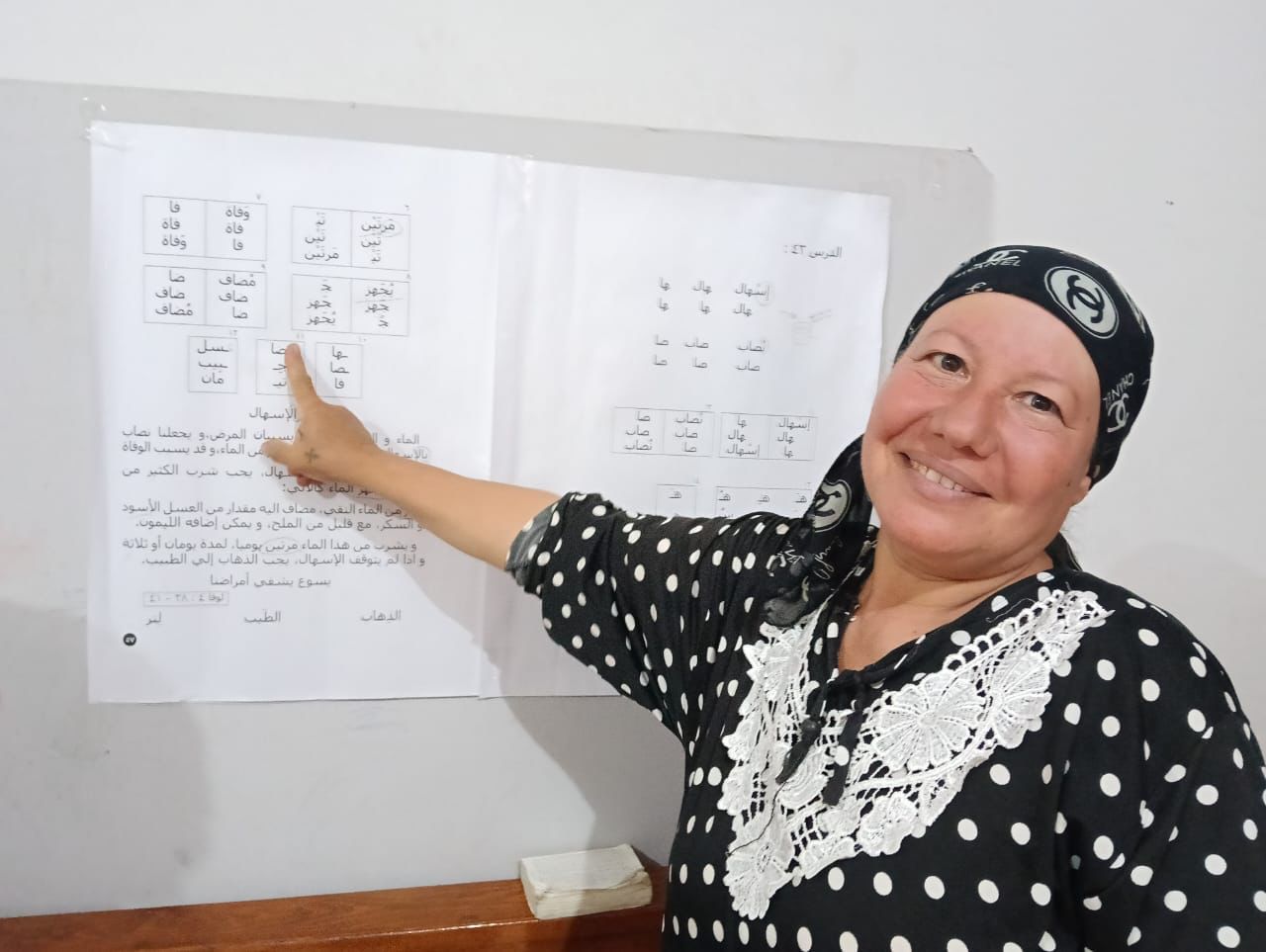 TCD adult student, Umm Aymen, pointing at the teaching board, showing what she is learning.