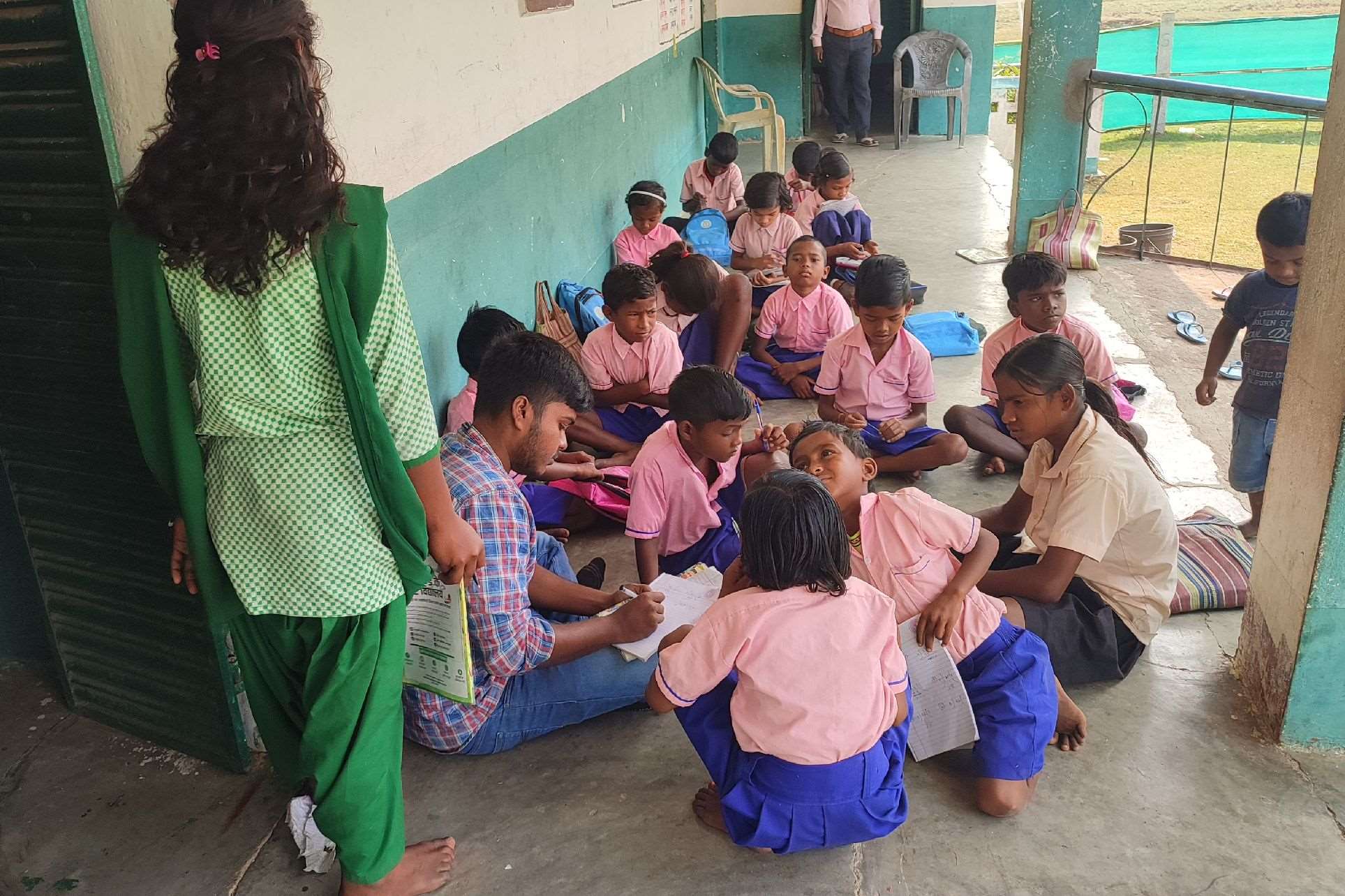 A large group of children in uniforms sitting on school grounds.