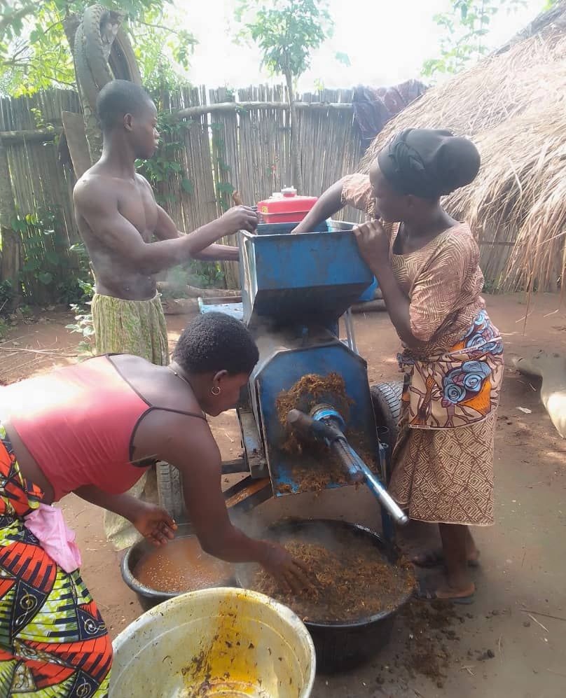 Three villagers working with their processing machine.