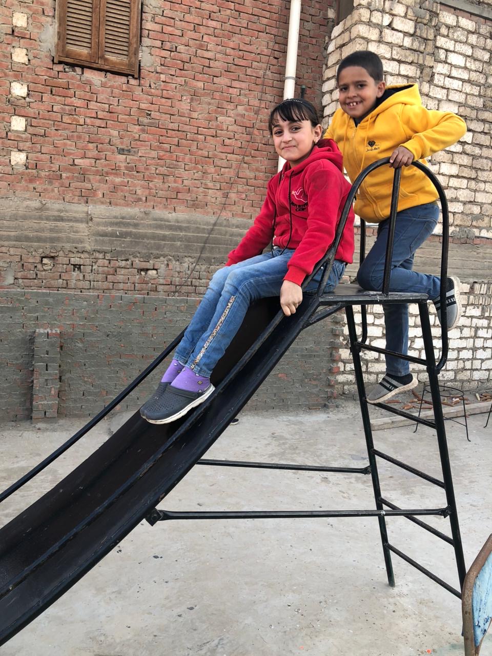 Two Egyptian children posing on the small metal slide.