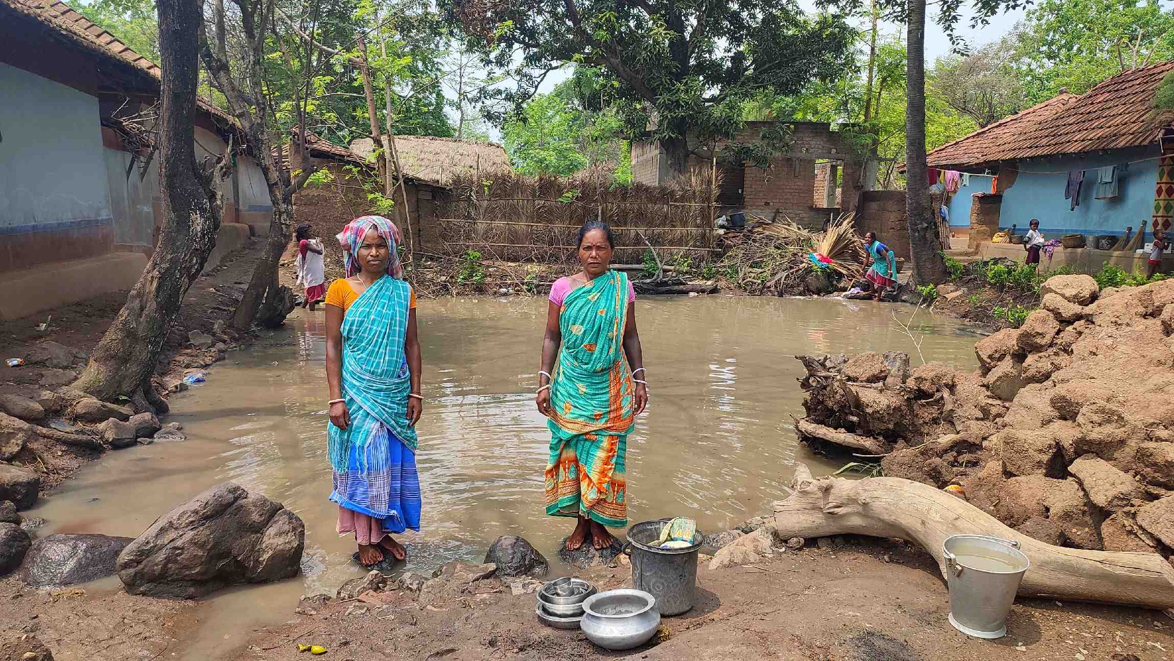 Two Indian villagers from Barmasia standing in front of unclean water.