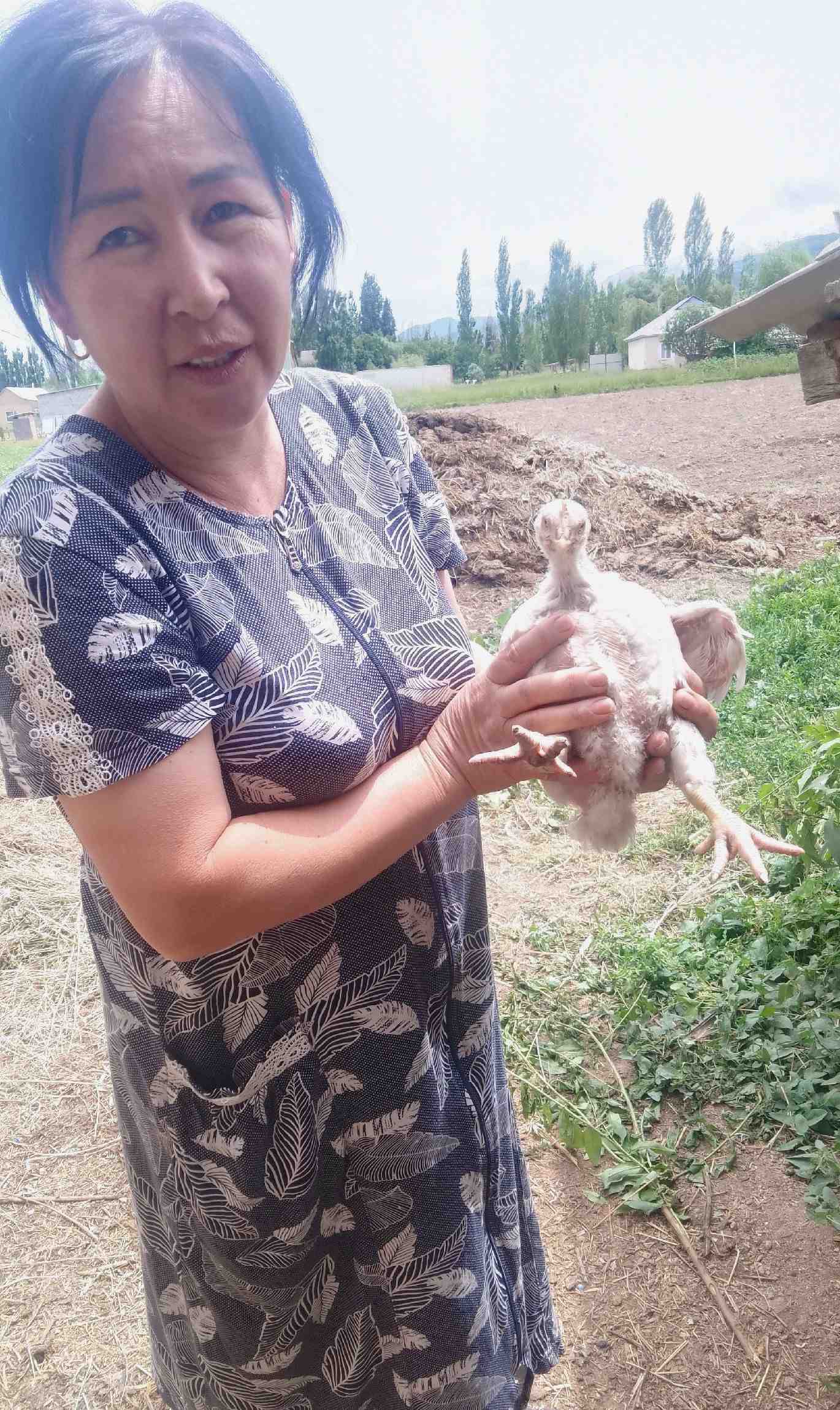 A Kyrgyzstan villager holding a chicken.