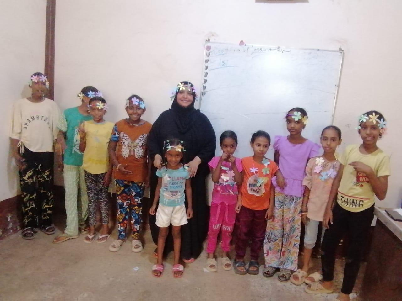 TCD attendant, Umm Shahd, with a group of children for a photo.