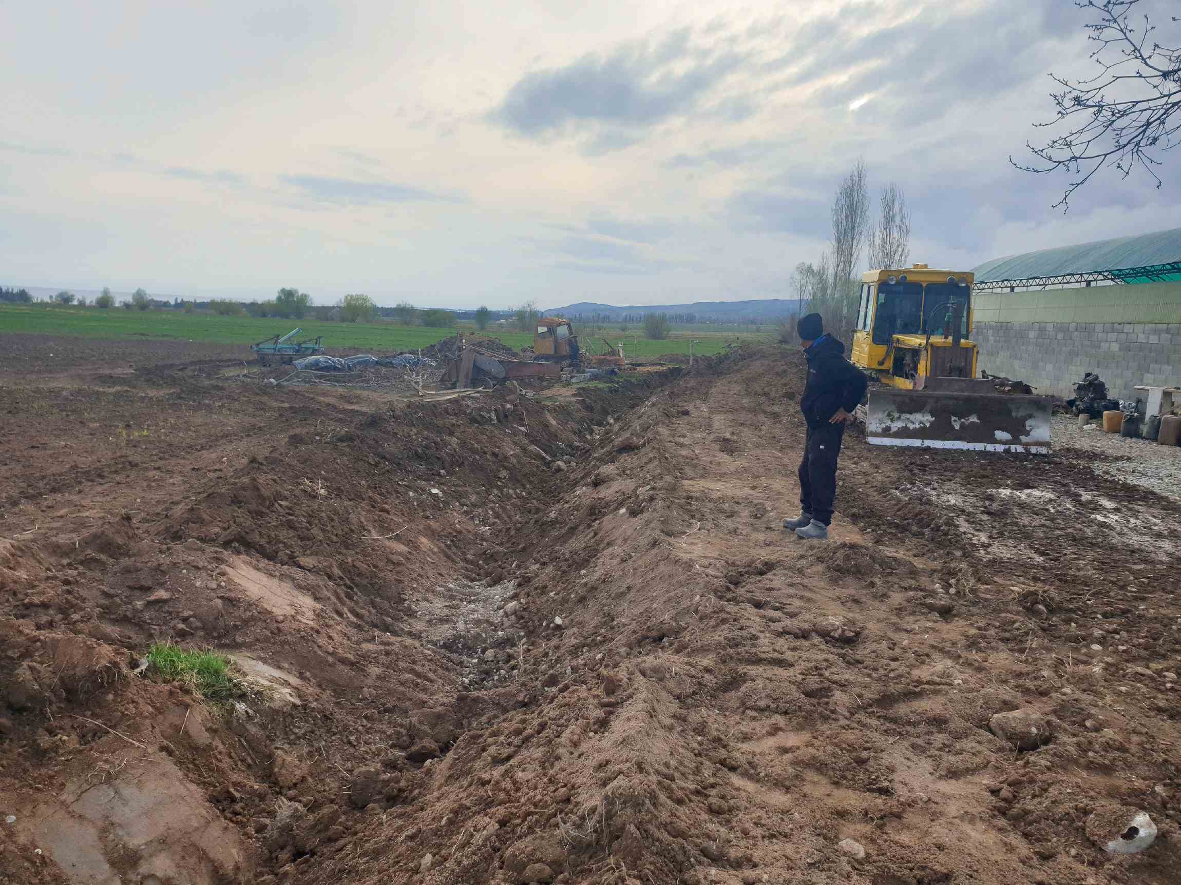 A Kyrgyzstan excavator checking the progress done to redirect water to a village.