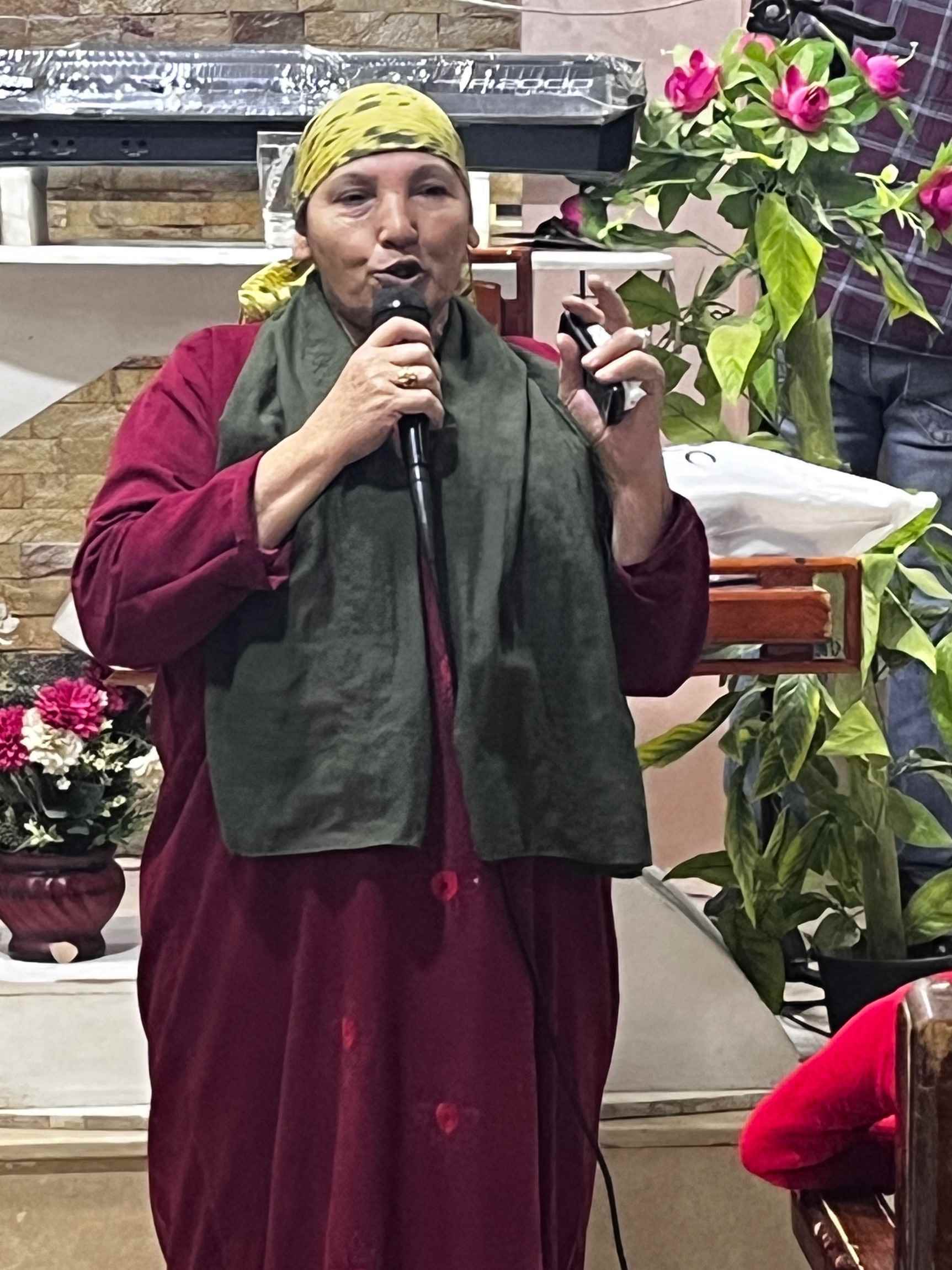 Haggana villager, Umm Kerlos, speaking on stage with a mic.