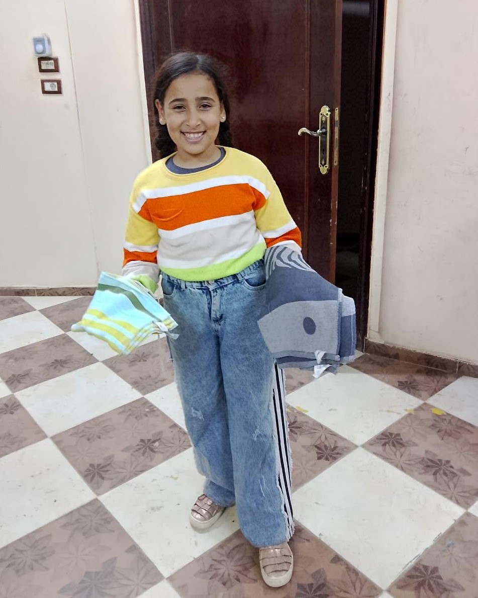 Al Koom Al Ahmar villager, Amy, showing the towels she received for her hygiene.