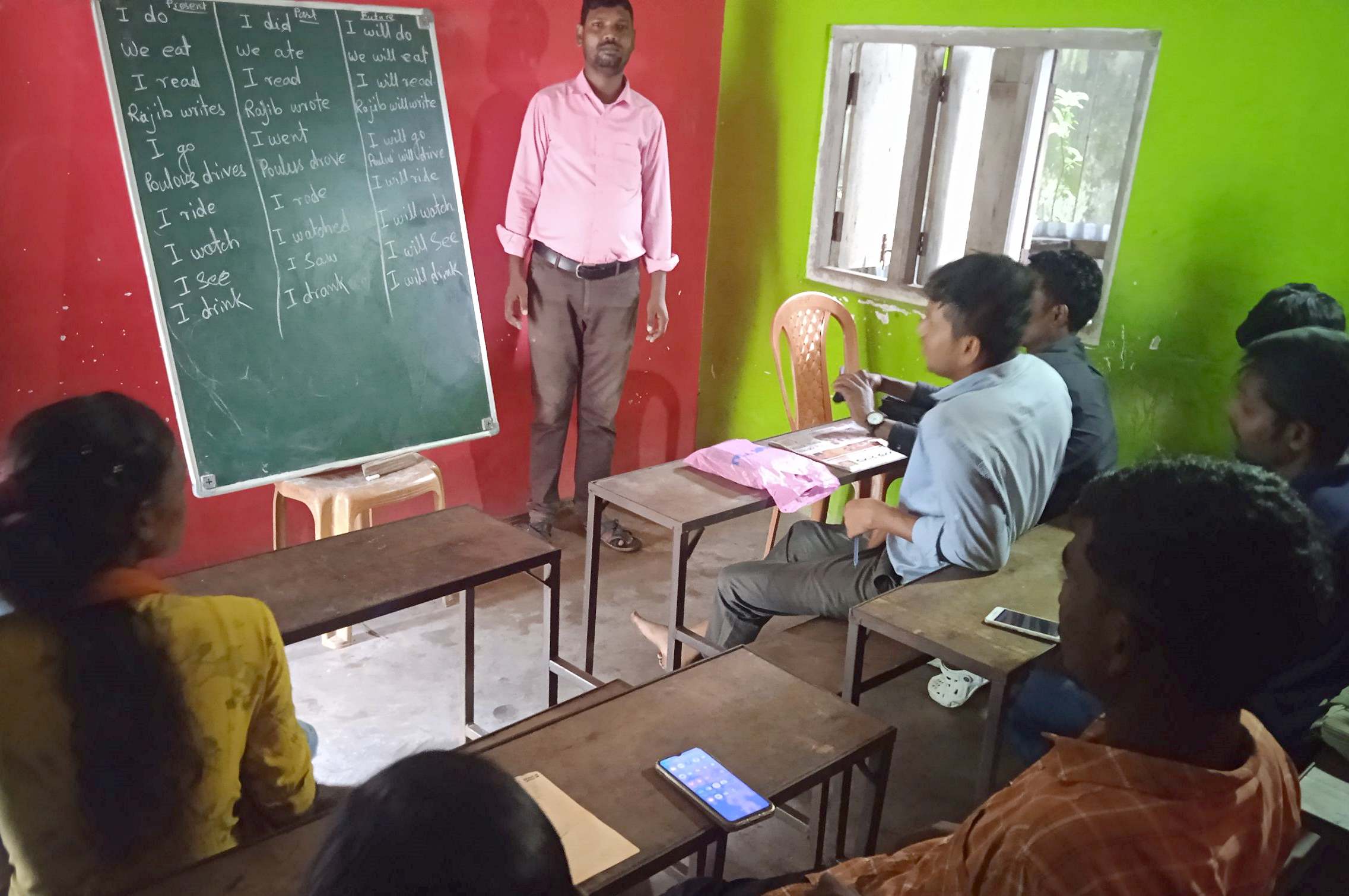 TCD worker, Anuj, teaching reading & writing.