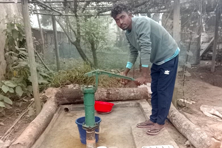 A Dapur male villager stands next to his new tubewell.