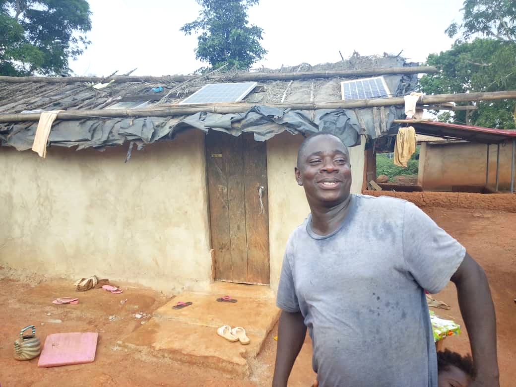 Effaoho villager, Romeo, standing in front of his house with new solar panels.