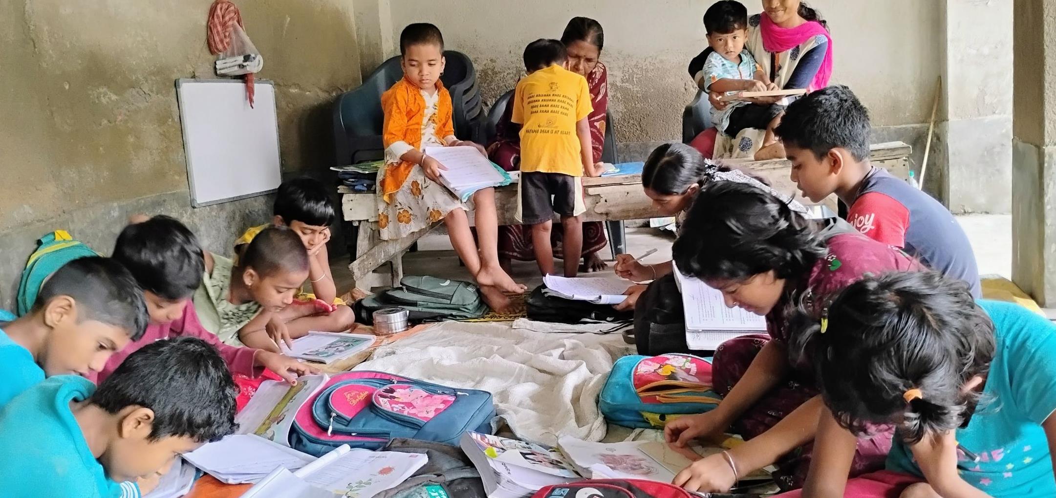 A Binodpur class in session as children sit & study with two teachers.