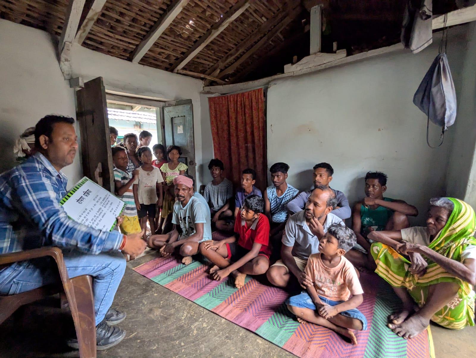 Shri Ambra villagers huddled in a small room as they take in a TCD lesson.