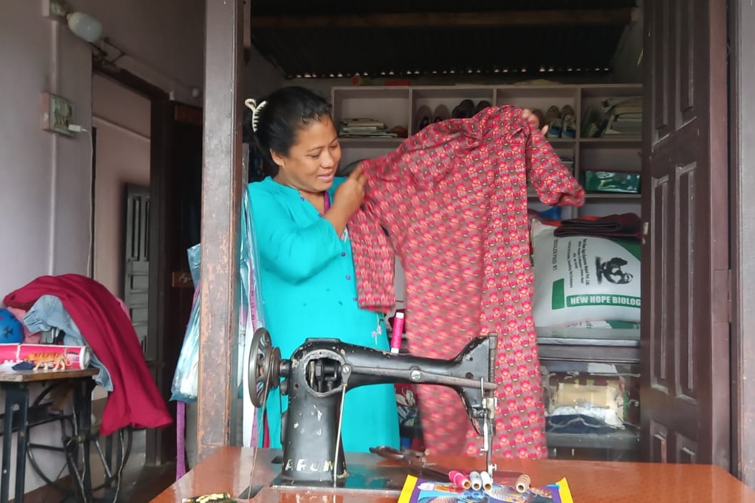 Ramantar female villager, Anita, showing a one piece outfit she's sewn.