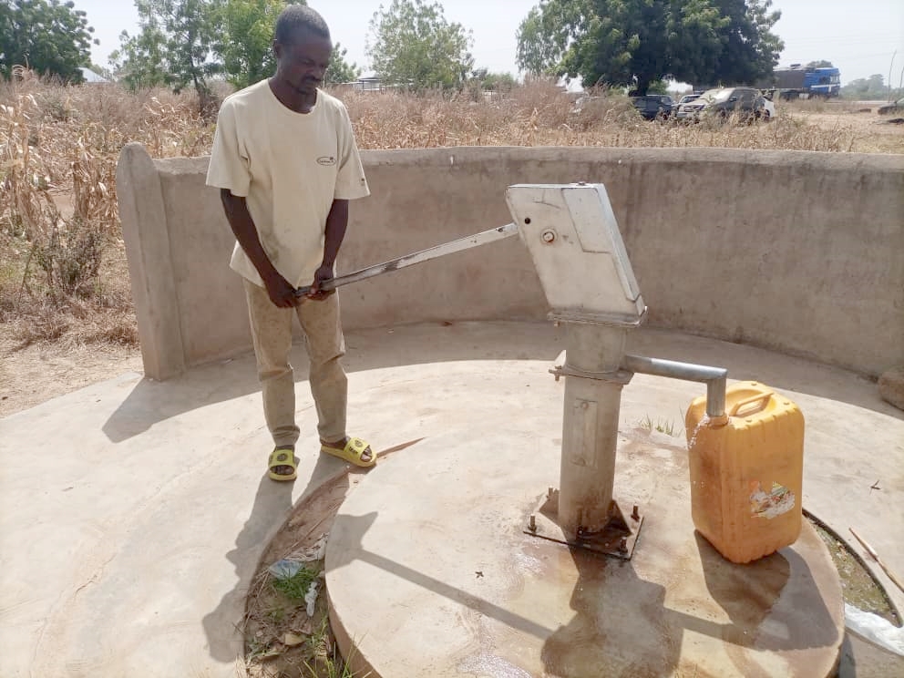 Batemone villager, Lamboni, pumping water in his plastic tank.