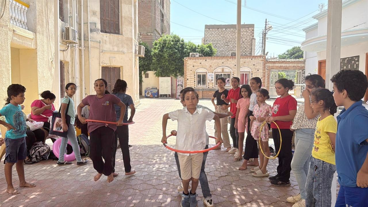 Children from the Upper Egypt Village Cluster playing a cooperative game involving hula hoops.
